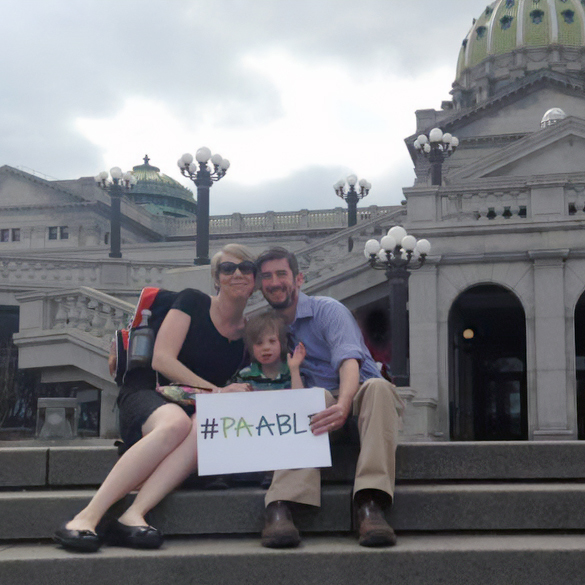 Seated on the steps of the capitol, the Skiffen Family Hold a sign that says #PAABLE